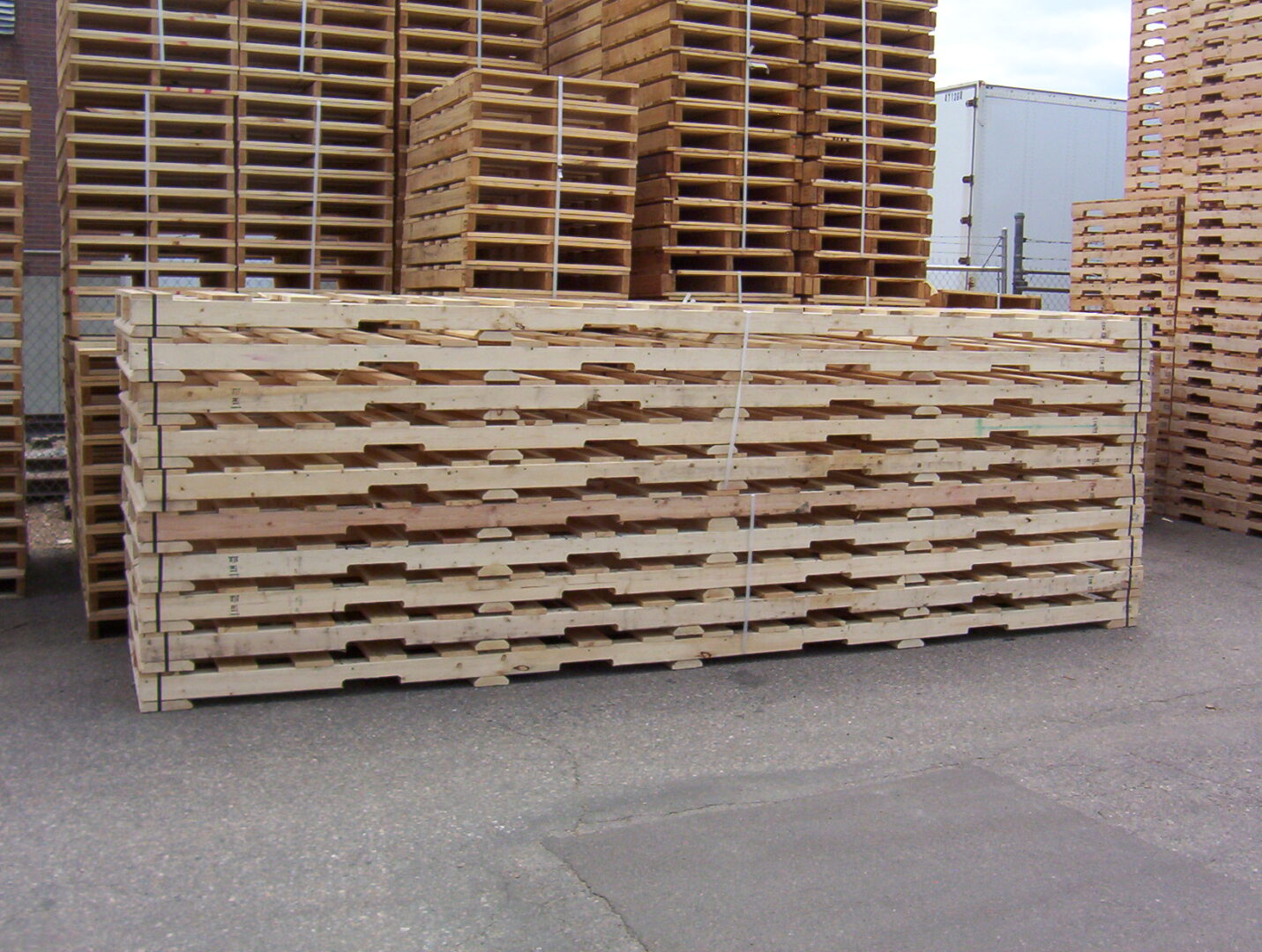 A pile of wooden pallets in front of many other pallets.